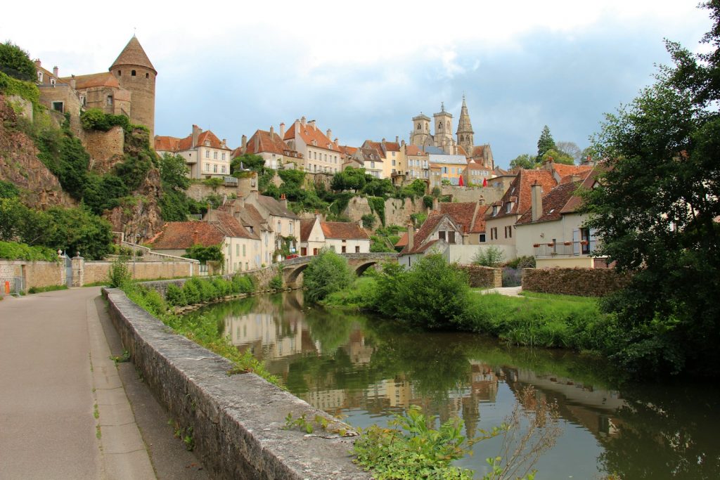 a river running through a village next to a lush green hillside